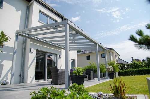 Weiße Terrassenüberdachung aus Aluminium mit Glaseindeckung an einem Einfamilienhaus